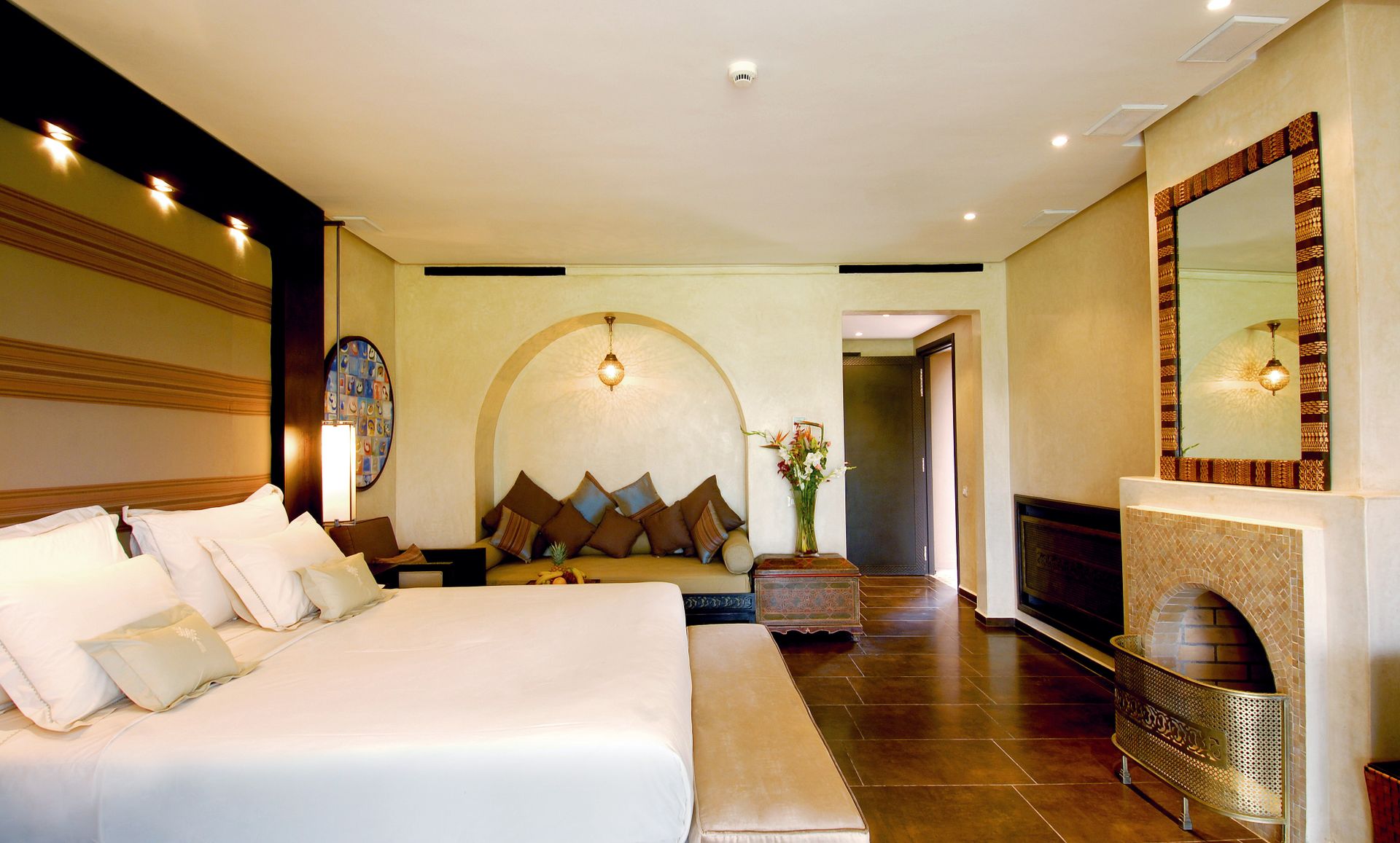 A warm boutique hotel suite with an arched alcove and mosaic fireplace